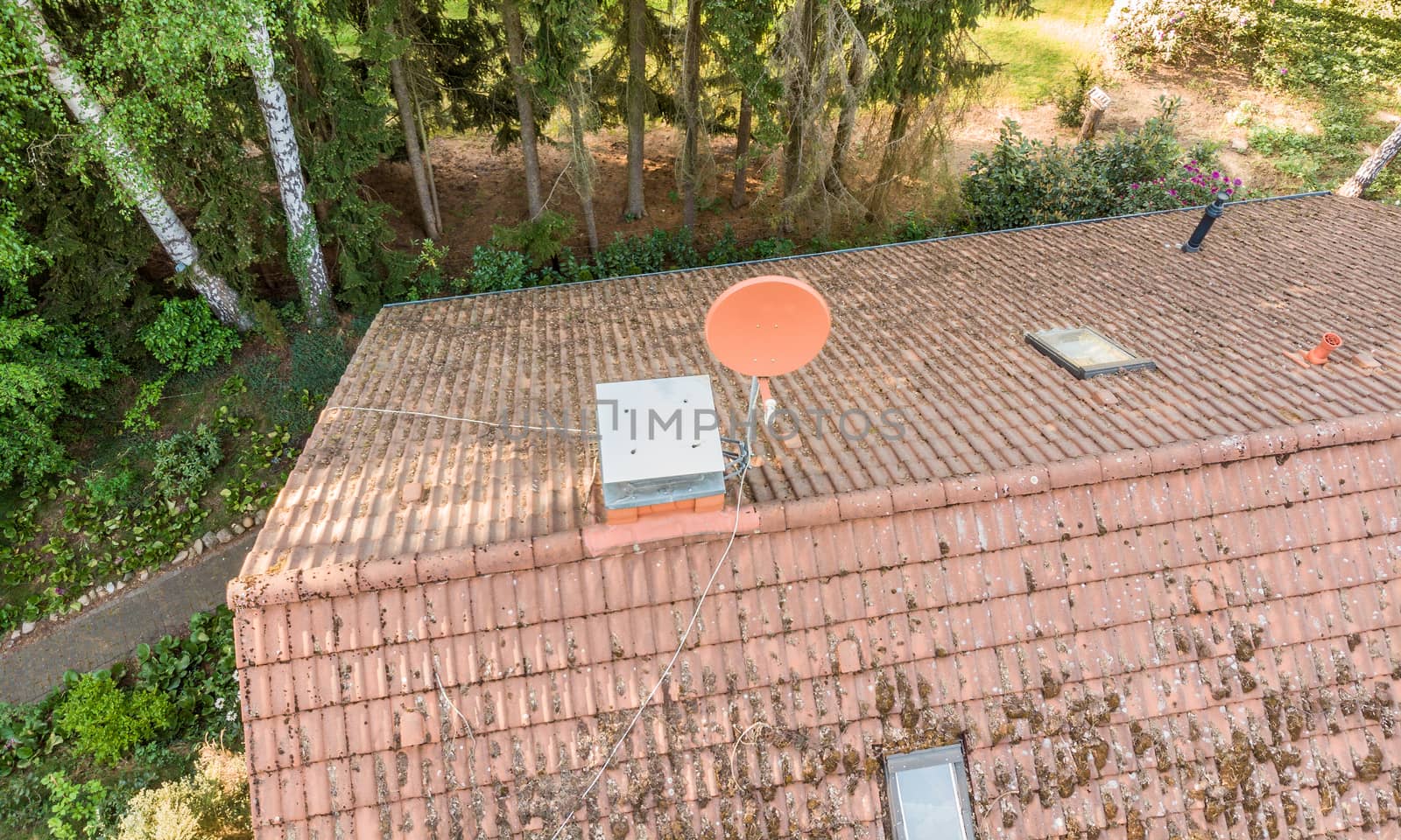 Overflight of the roof of a detached house to check the condition of the satellite antenna for the reception of television and Internet, aerial view made with drone