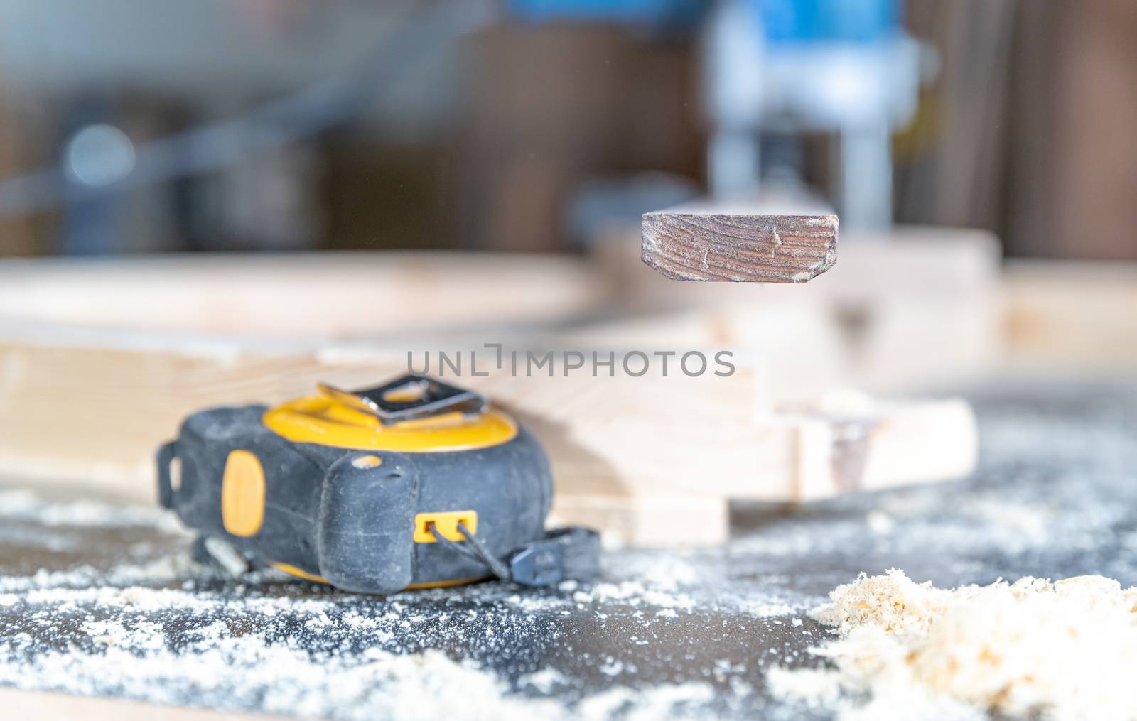 Retractable measuring tape on a desk with sawdust in joinery.