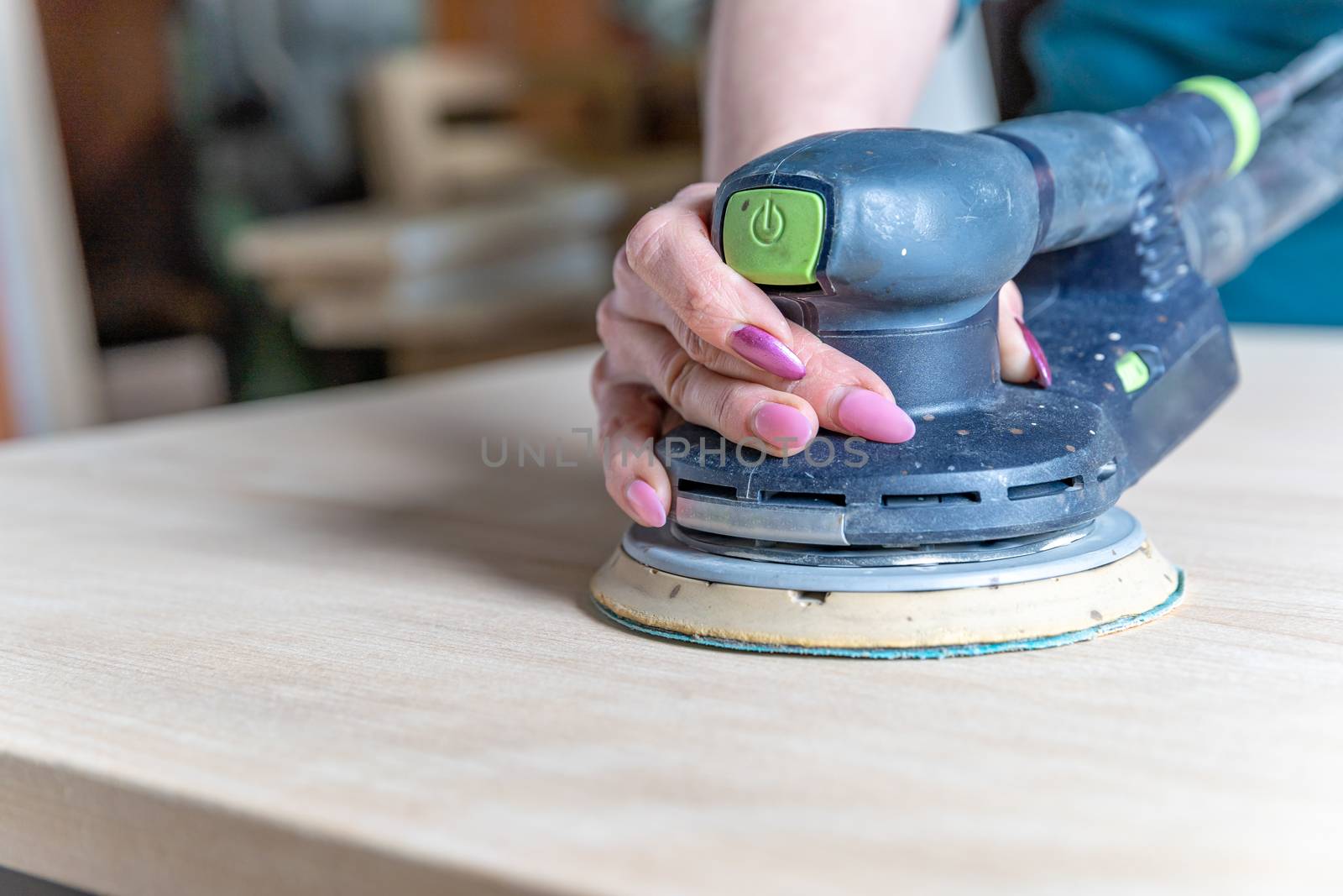 sanding wooden furniture using an electric hand grinder.