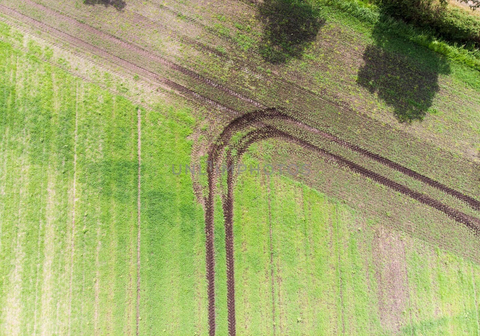 track of a tractor on a field which has made a turn when reaching the field boundary, abstract effect by vertical aerial view, to be used as background, made with drone