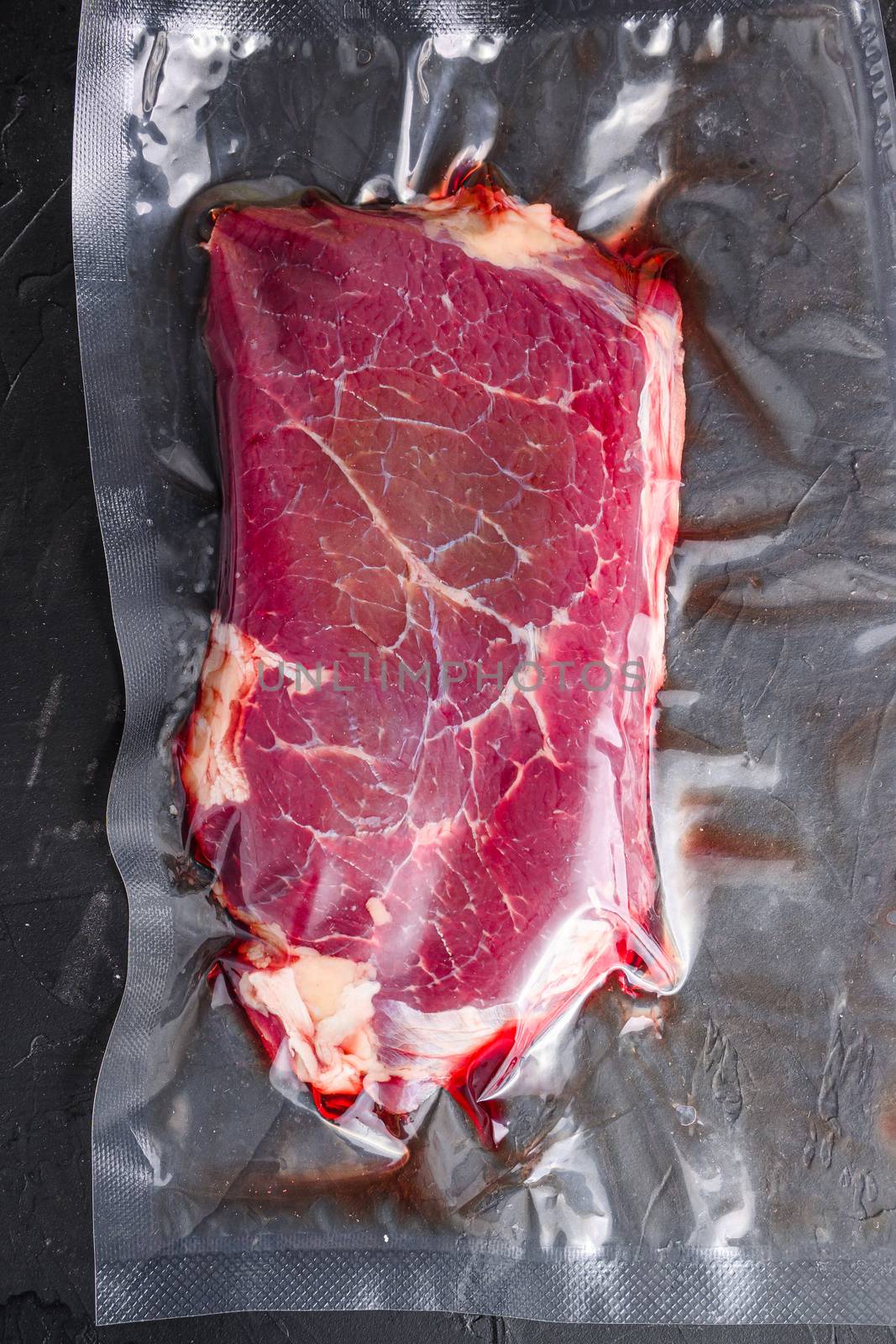 Rump beef steak for sous vide cooking on black stone background, top view