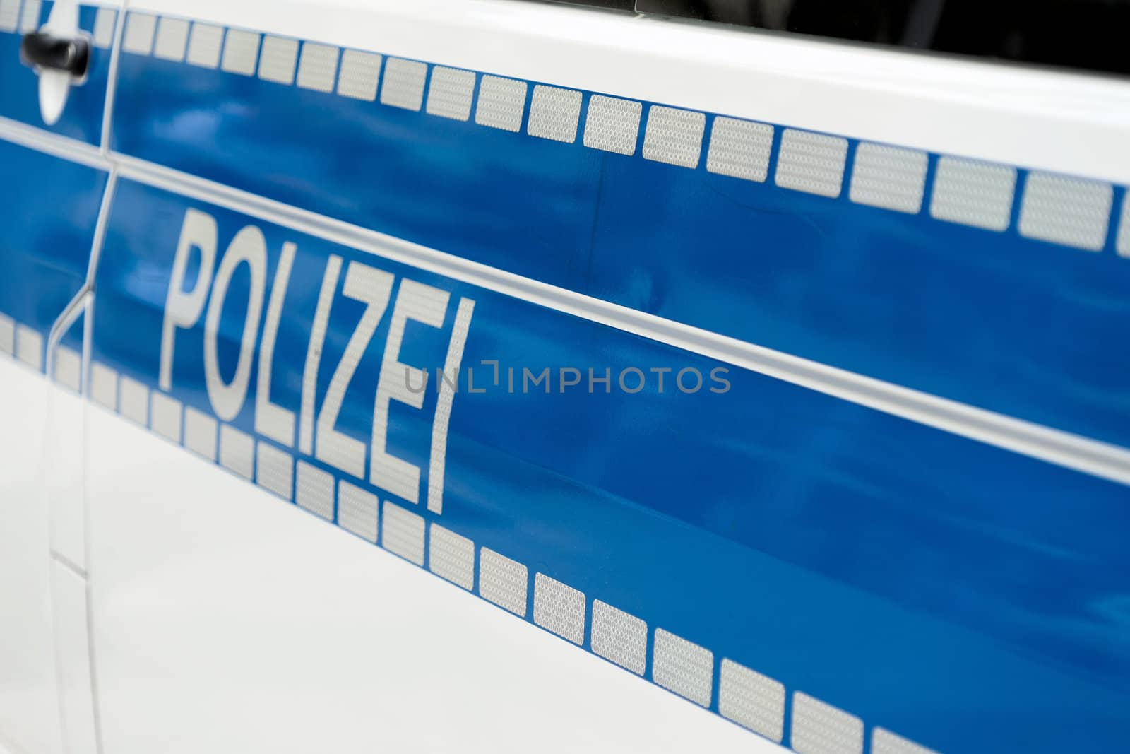 Inscription "Police" in white luminous colour on a blue background on the side of a police car, Germany