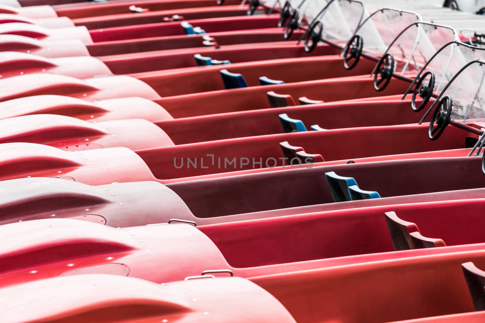 Abstract photo of red pedal boats moored at the jetty on a lake by geogif