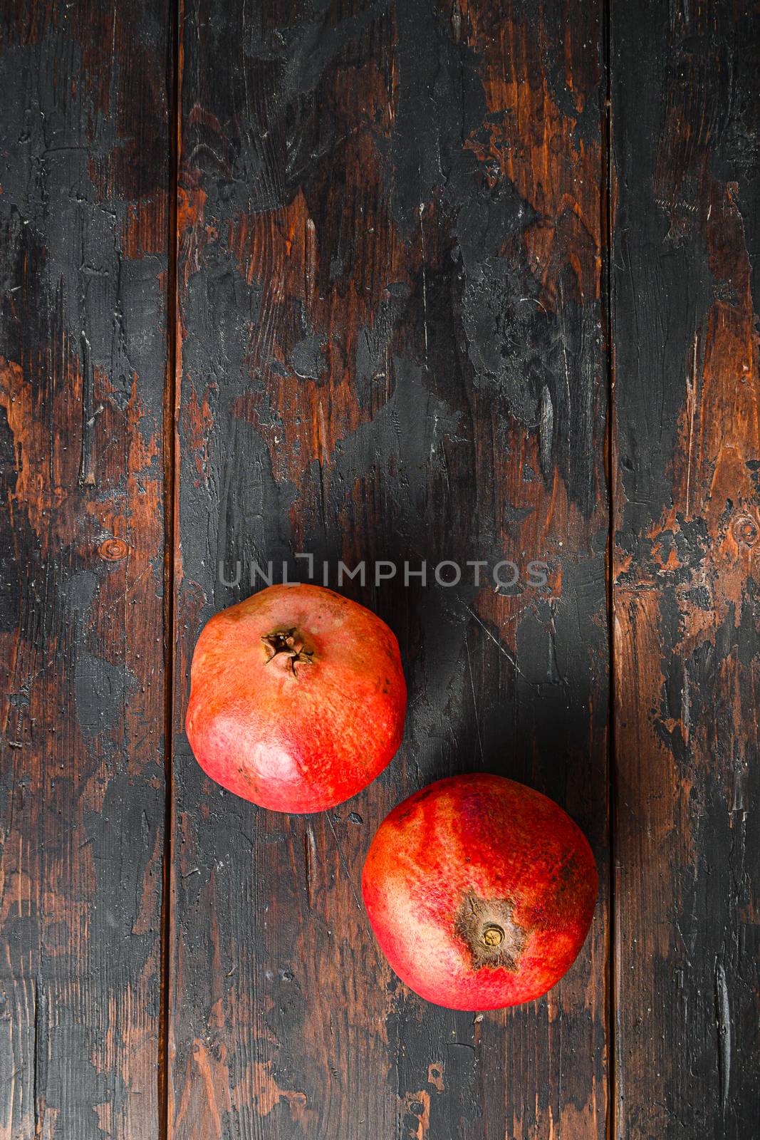 Ripe pomegranates over dark old wooden table, top view with space for text