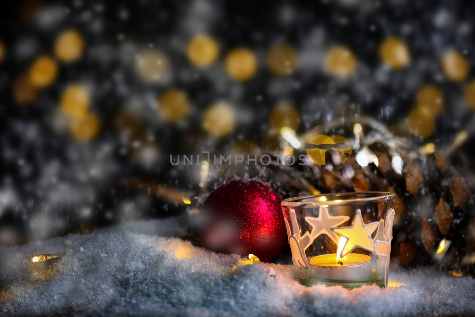 christmas theme with candles, snow, pine cone and christmas light with pokeh effect