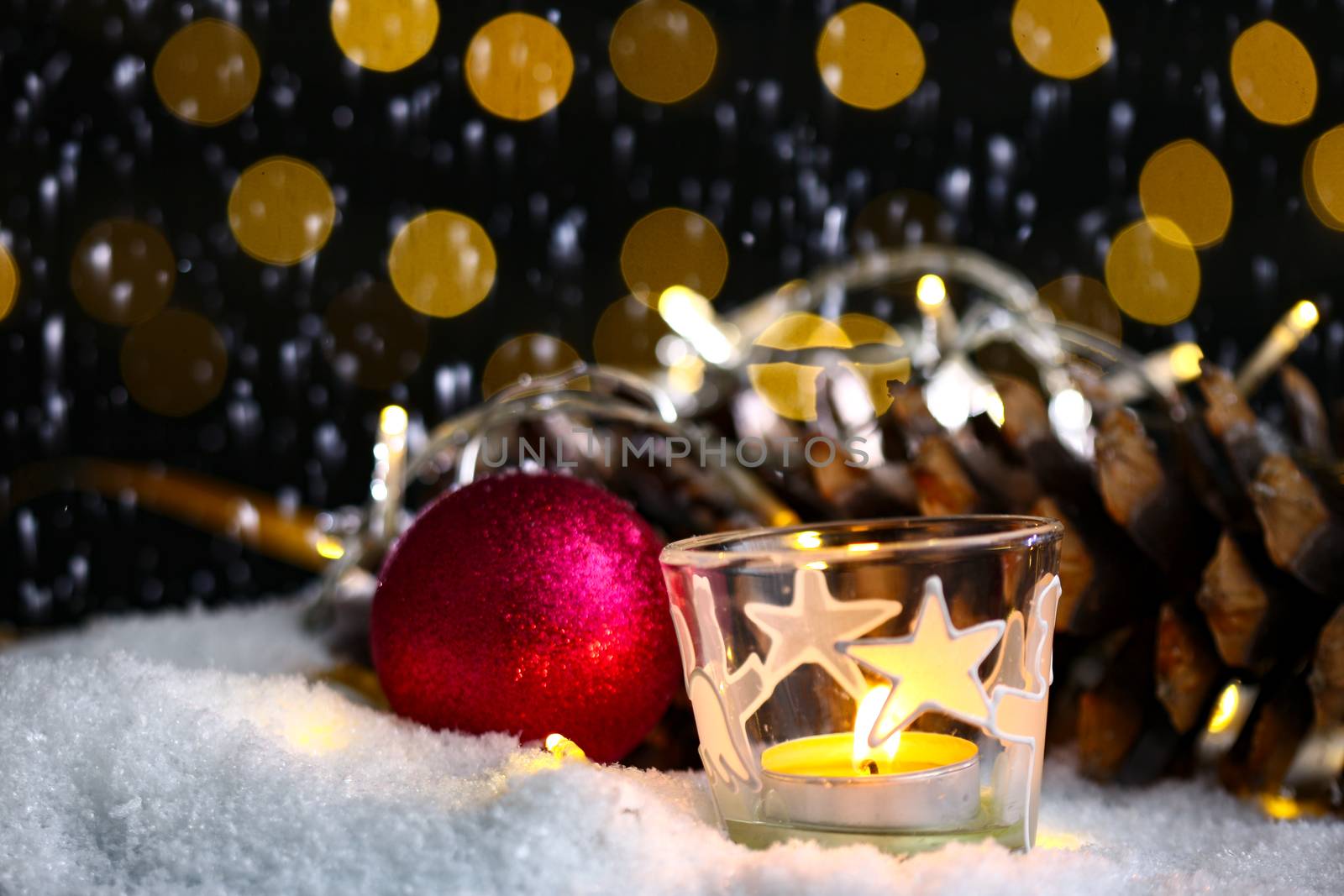 christmas theme with candles, snow, pine cone and christmas light with pokeh effect