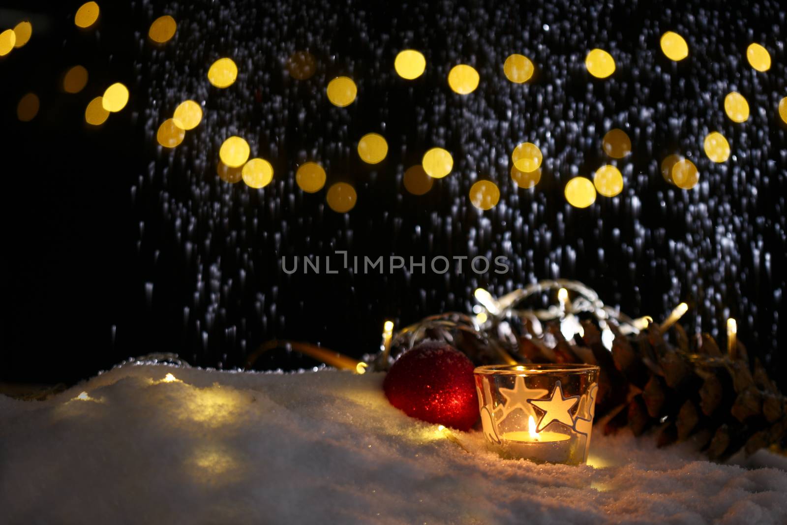 christmas theme with candles, snow, pine cone and christmas light with pokeh effect