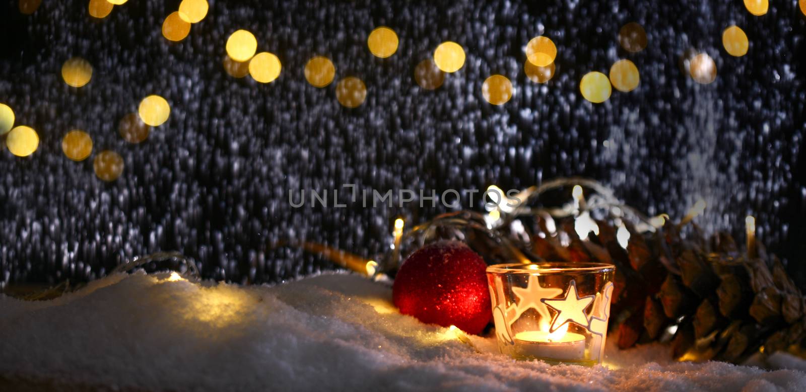 christmas theme with candles, snow, pine cone and christmas light with pokeh effect