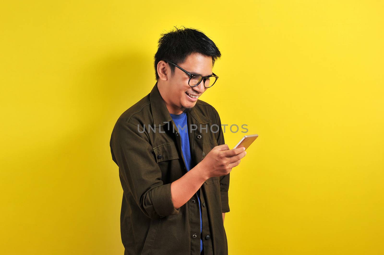 Portrait of happy smiling Asian man using smartphone wearing cas by heruan1507