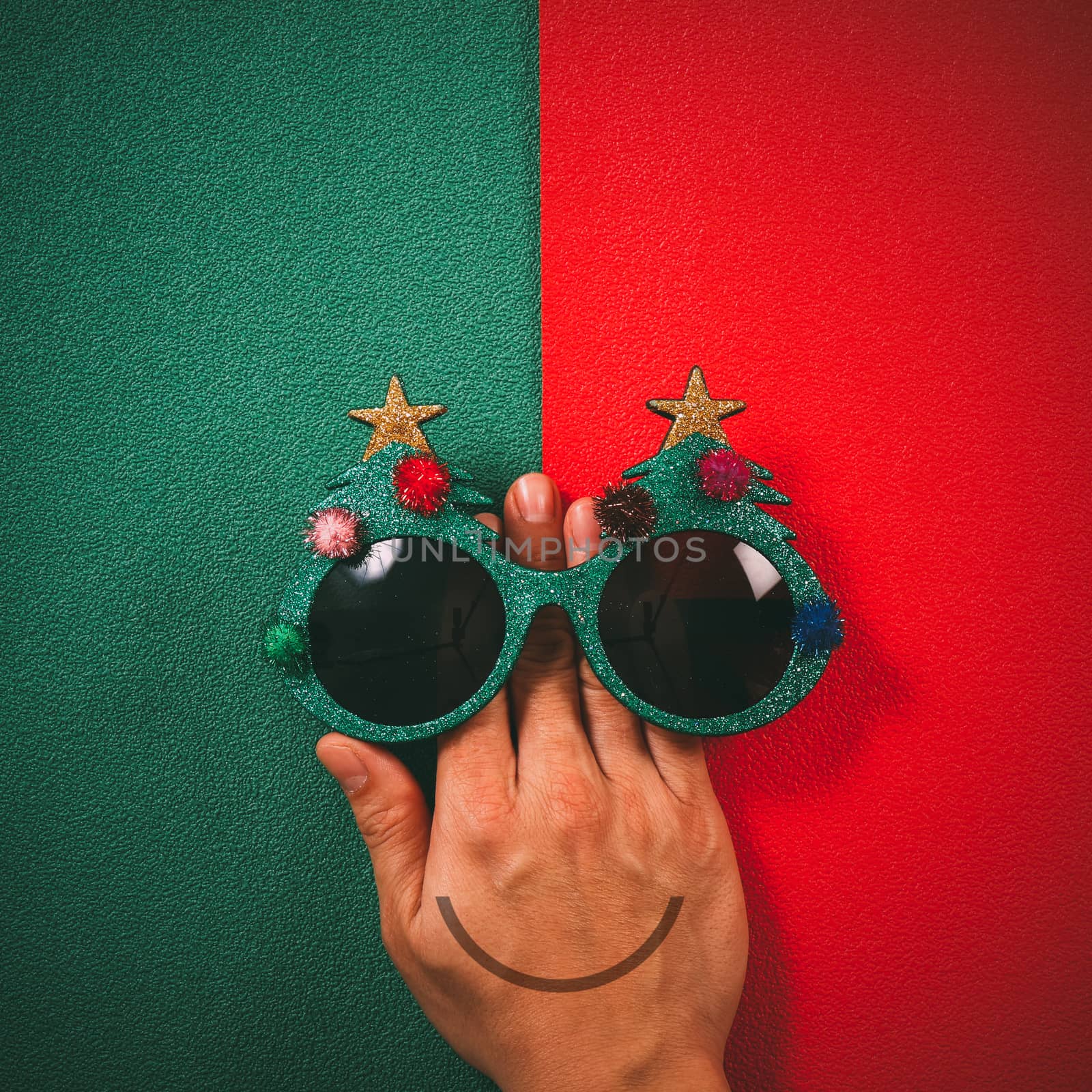 Christmas glasses that decoration with Christmas tree and red ball on hand on green and red  background