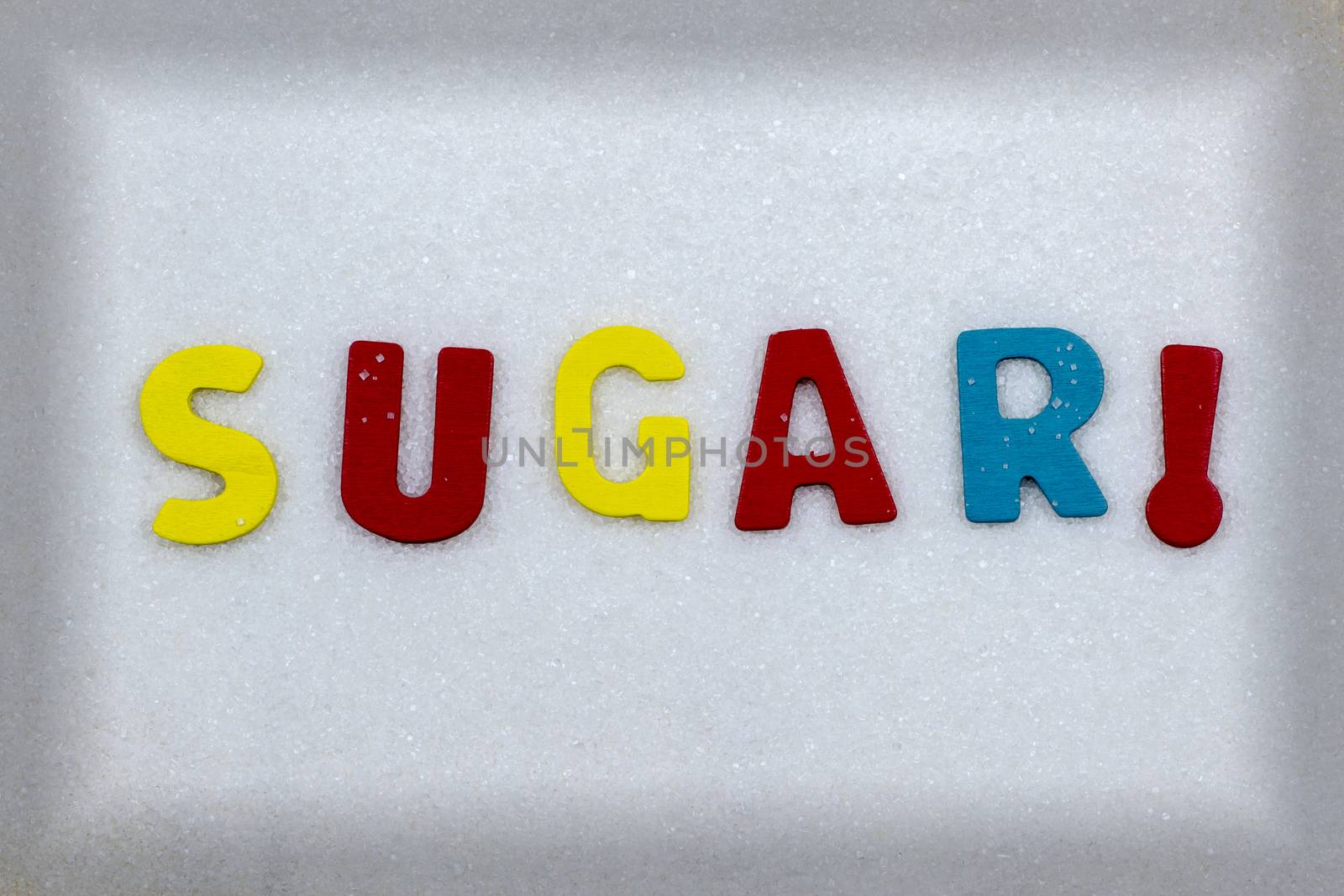 "SUGAR!" Colorful text and letters in wood on white sugar crystals background and light black frame