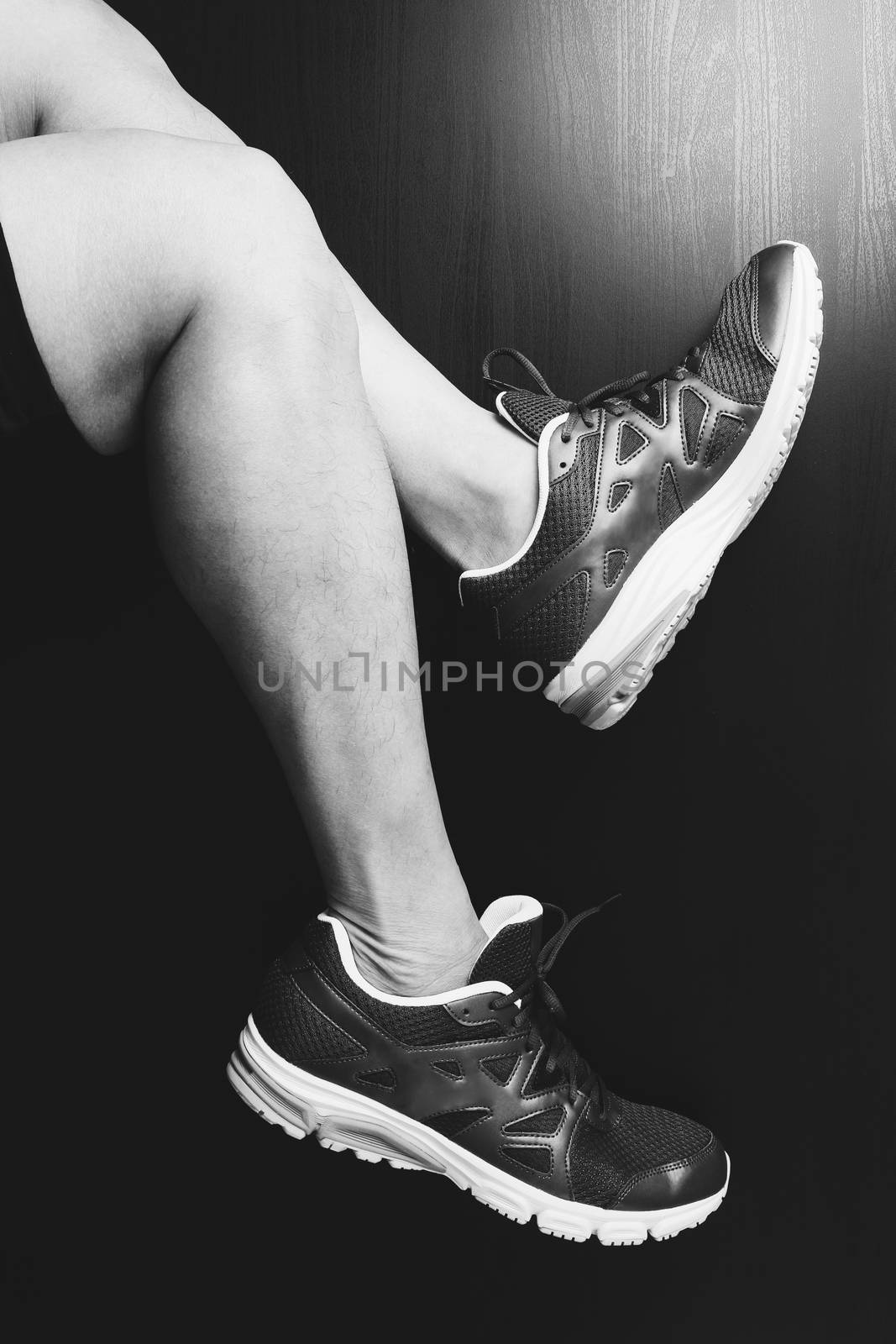 Runner sportsman holding ankle in pain with Broken twisted joint running sport injury and Athletic man touching foot due to sprain,black and white