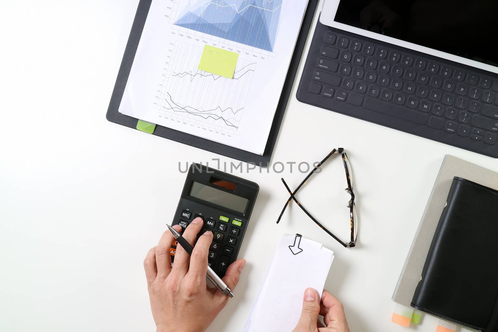 top view of businessman hand working with finances about cost and calculator and latop with mobile phone on withe desk in modern office 