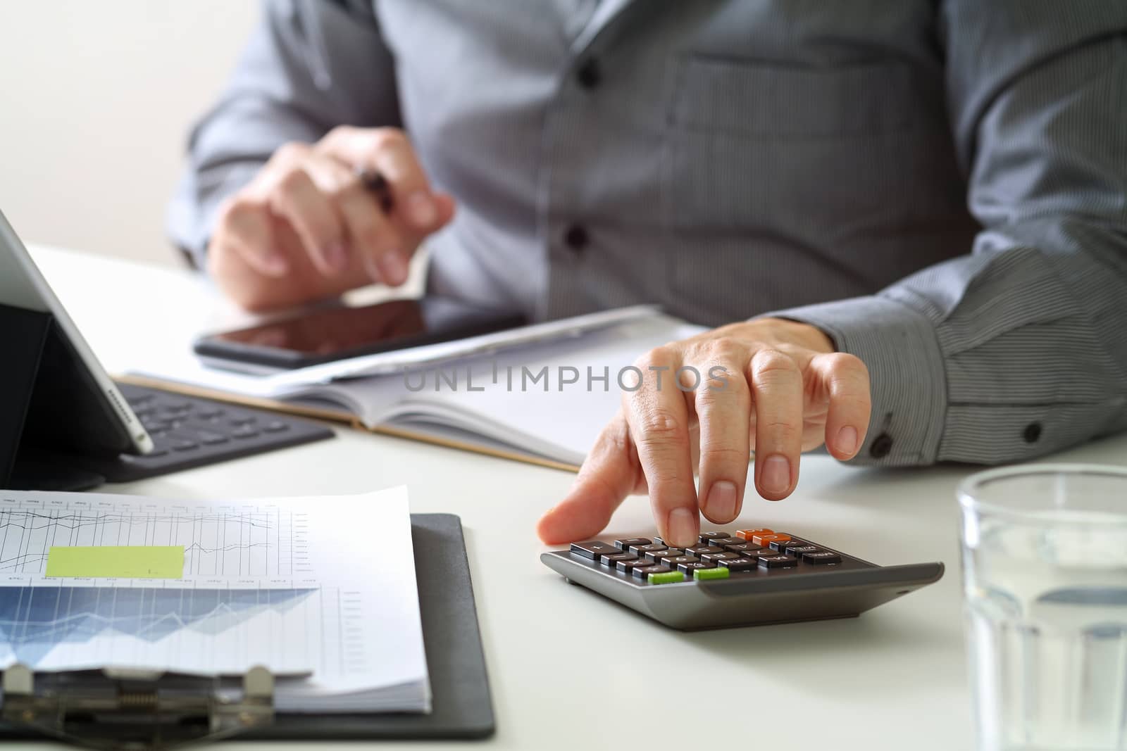 businessman hand working with finances about cost and calculator and latop with mobile phone on withe desk in modern office with VR icon diagram