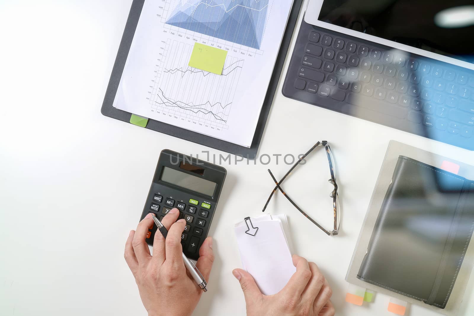 top view of businessman hand working with finances about cost and calculator and latop with mobile phone on withe desk in modern office 