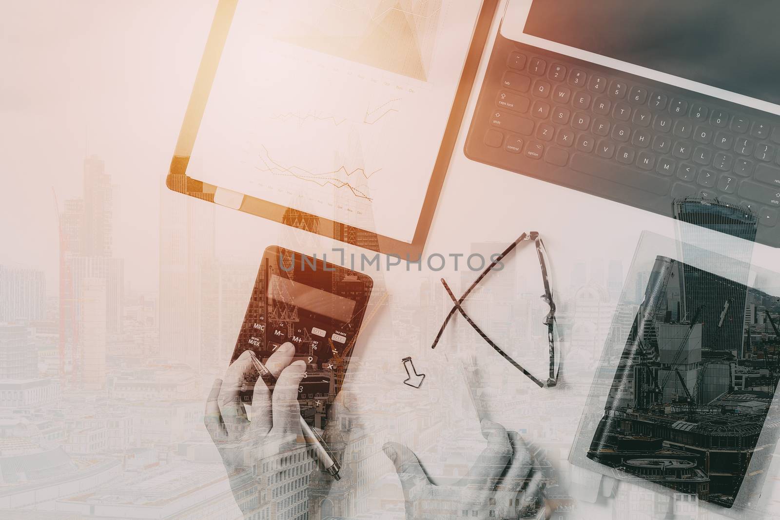 top view of businessman hand working with finances about cost and calculator and latop with mobile phone on withe desk in modern office with building exposure