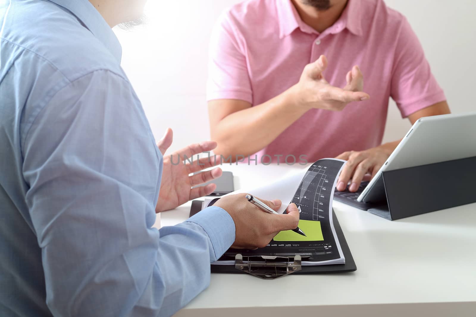 Businessmen working together on a document and using smart phone and digital tablet and laptop computer in modern office                                                     