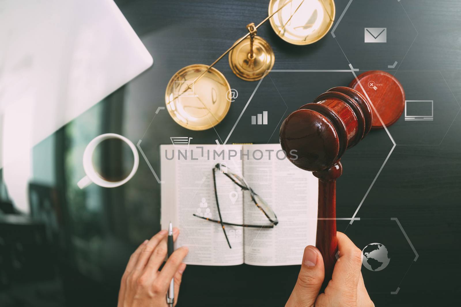 justice and law concept.Top view of Male judge hand in a courtroom with the gavel and brass scale and computer and open bible book on dark wood table with Vr diagram