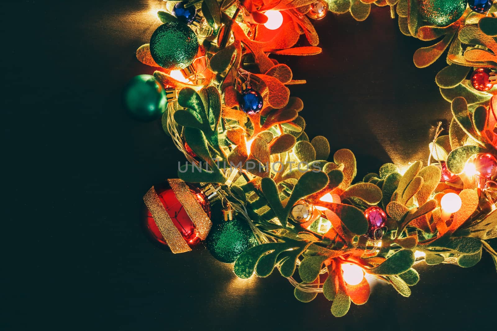 Greeting Season concept.Christmas wreath with decorative light on dark wood background