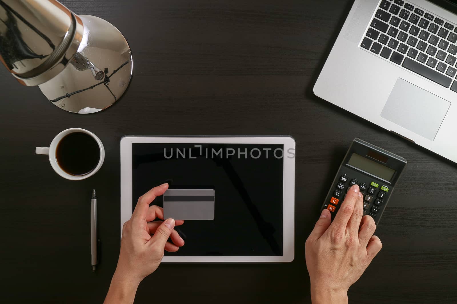 Internet shopping concept.Top view of hands working with laptop and credit card and tablet computer on dark wooden table background