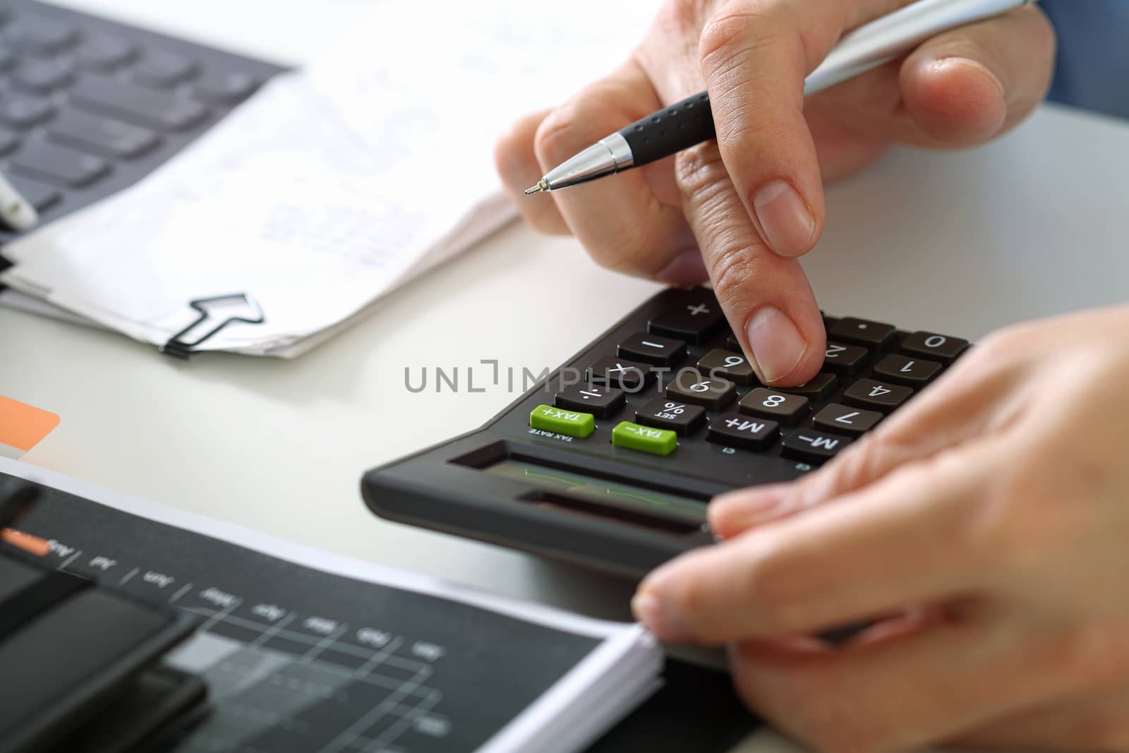 close up of businessman hand working with finances about cost and calculator and latop with mobile phone on withe desk in modern office