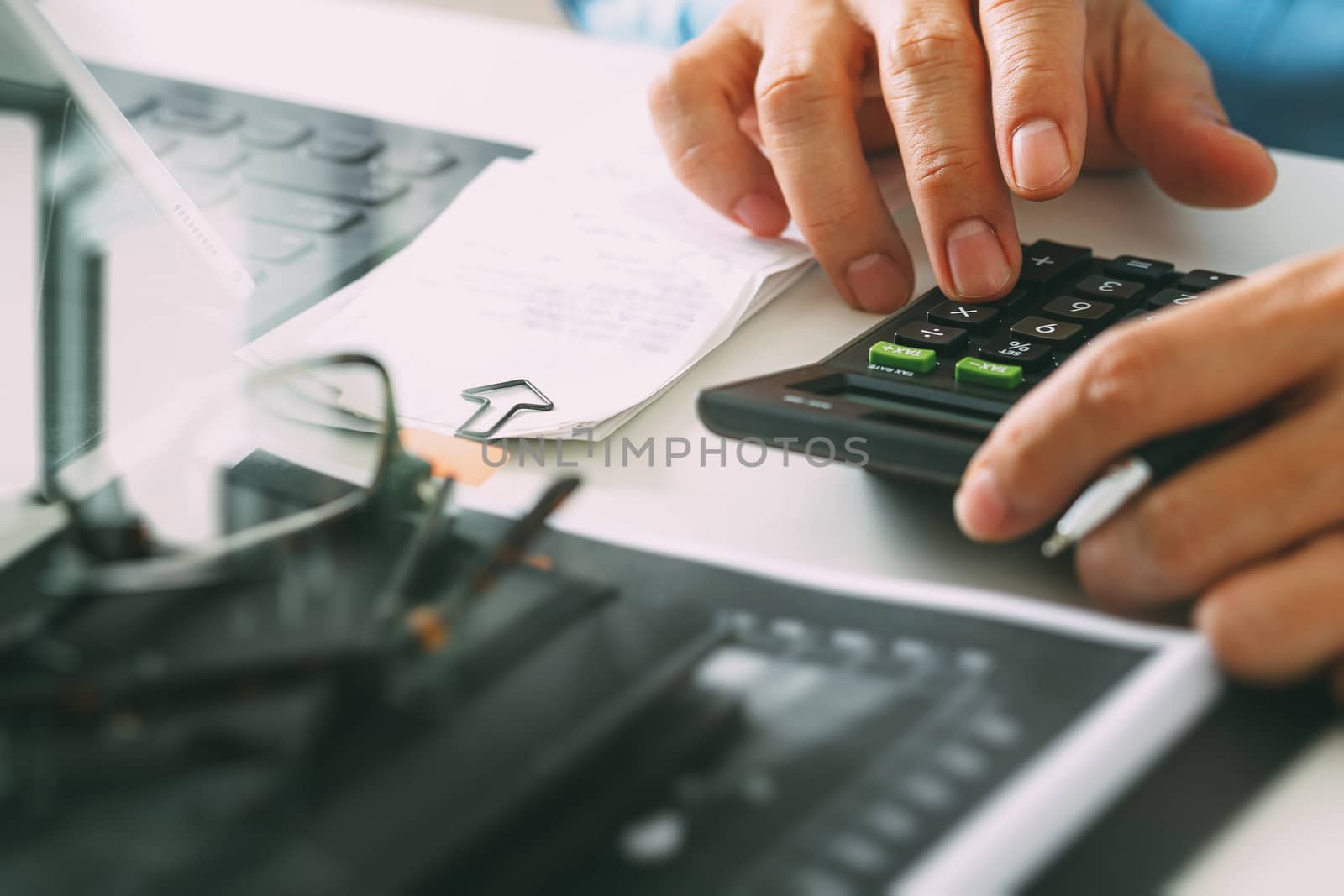 close up of businessman hand working with finances about cost and calculator and latop with mobile phone on withe desk in modern office