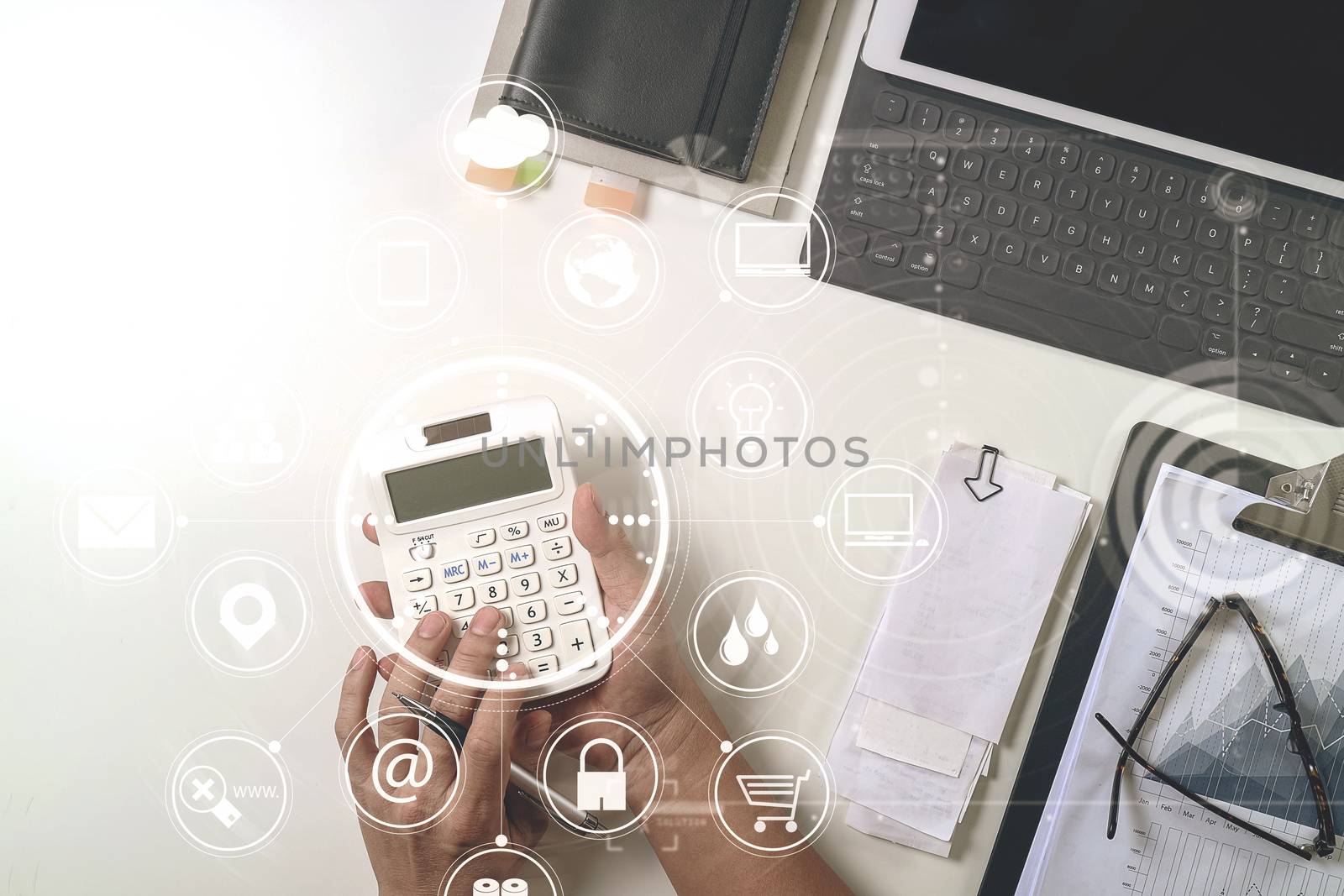 top view of businessman hand working with finances about cost and calculator and latop with mobile phone on withe desk in modern office with VR icon diagram