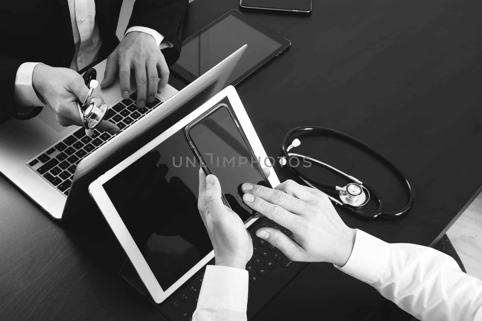 Medical co working concept,Doctor working with smart phone and digital tablet and laptop computer to meeting his team in modern office at hospital,black and white