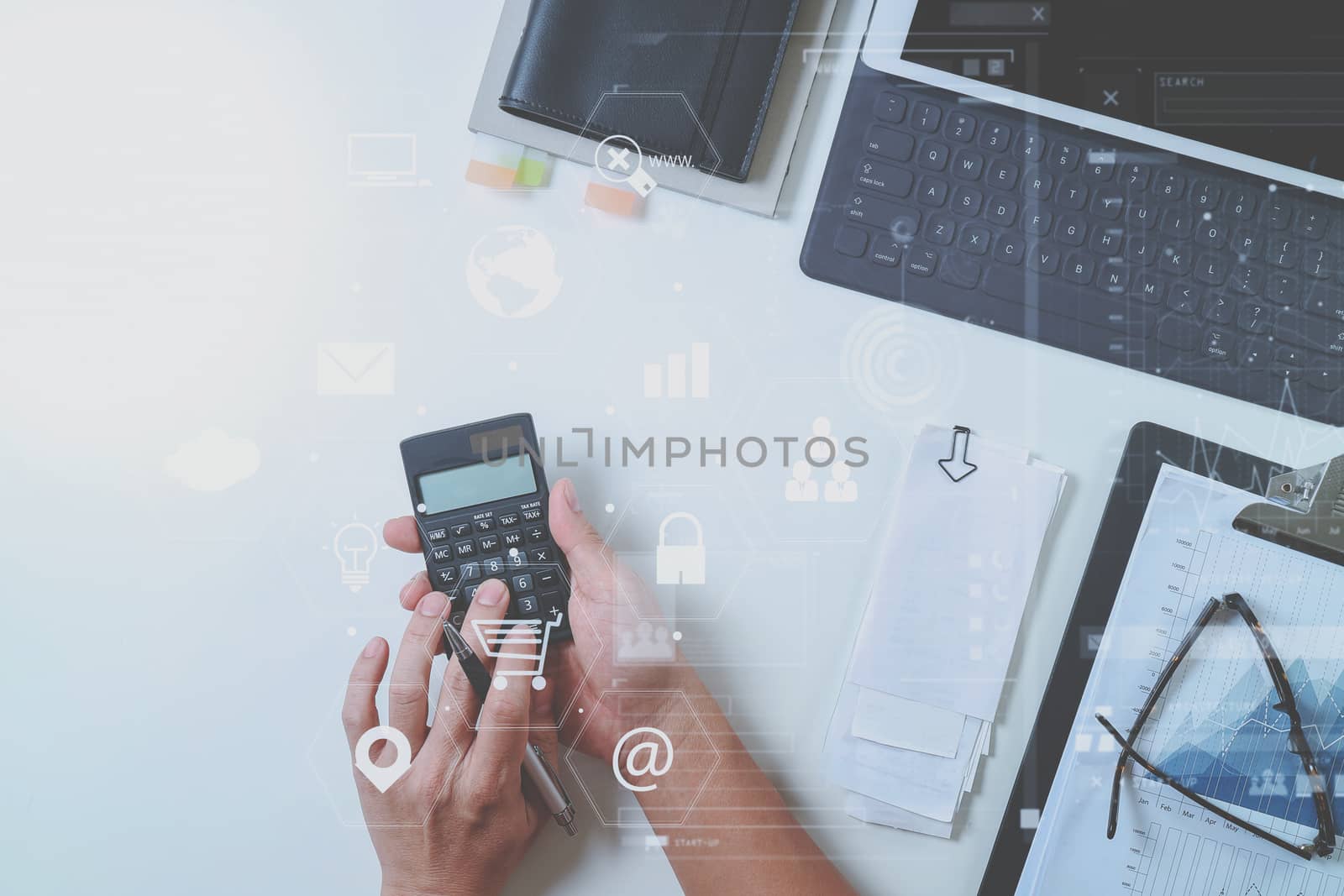 top view of businessman hand working with finances about cost and calculator and latop with mobile phone on withe desk in modern office with VR icon diagram