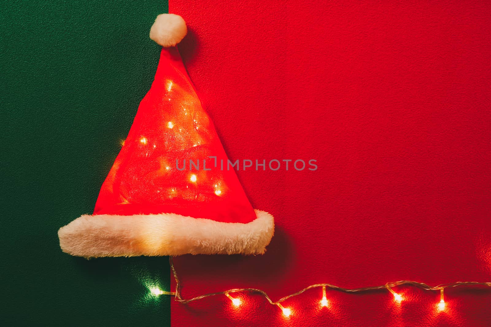 Greeting Season concept.Santa Claus hat with christmas light on red and green background