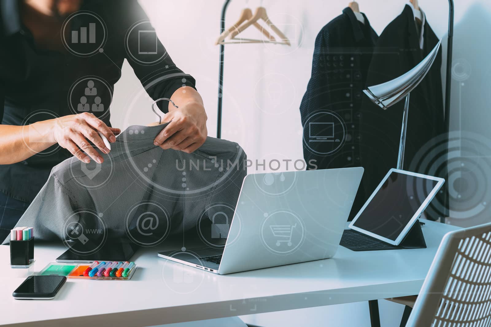 Fashion designer holding shirt and using laptop with digital tab by everythingpossible