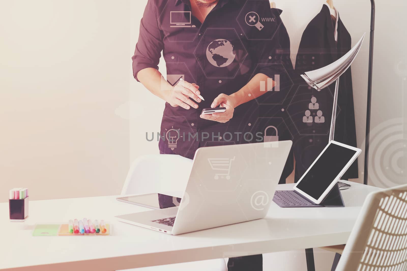 Fashion designer working with mobile phone and using laptop with digital tablet computer in modern studio with VR icon diagram