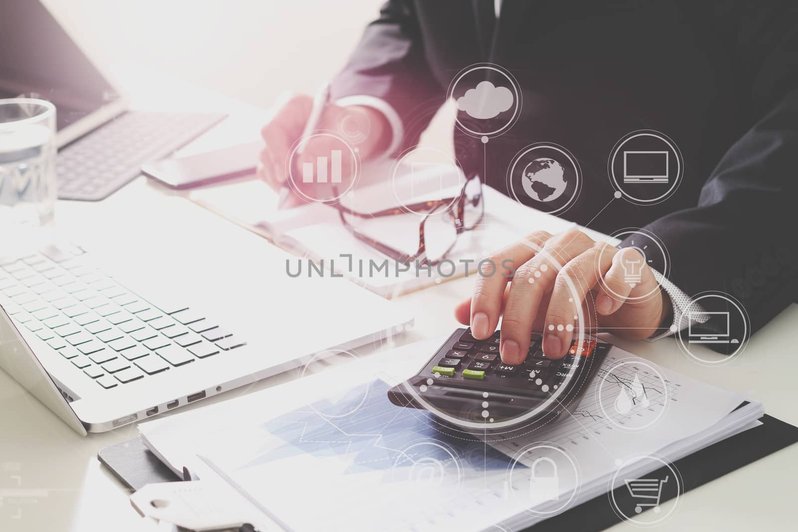 businessman hand working with finances about cost and calculator and latop with mobile phone on withe desk in modern office with VR icon diagram