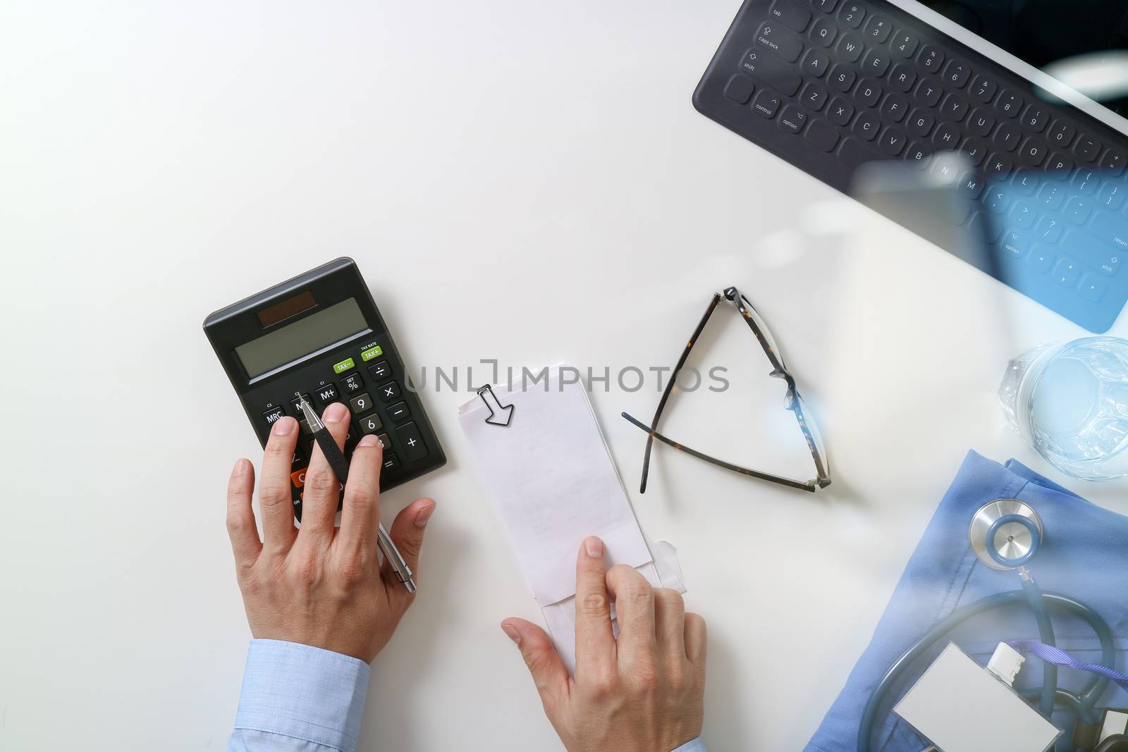 top view of Healthcare costs and fees concept.Hand of smart doctor used a calculator for medical costs in modern hospital 