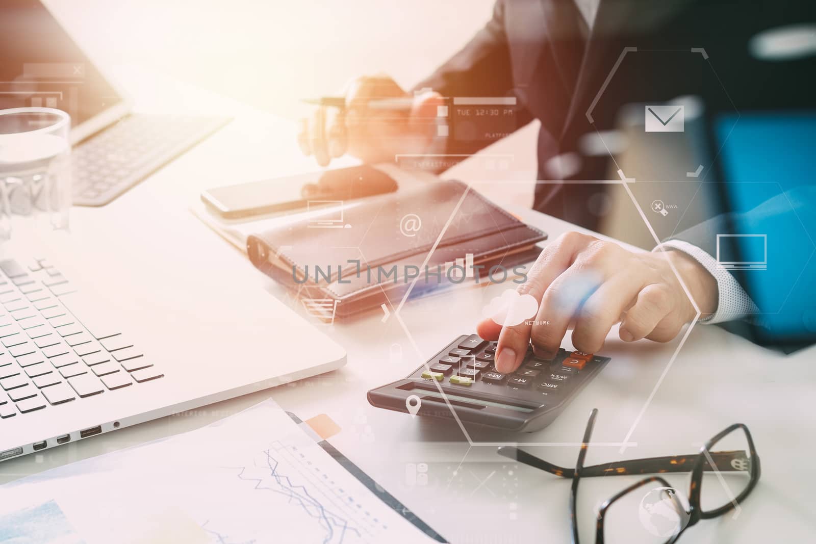 businessman hand working with finances about cost and calculator and latop with mobile phone on withe desk in modern office with VR icon diagram