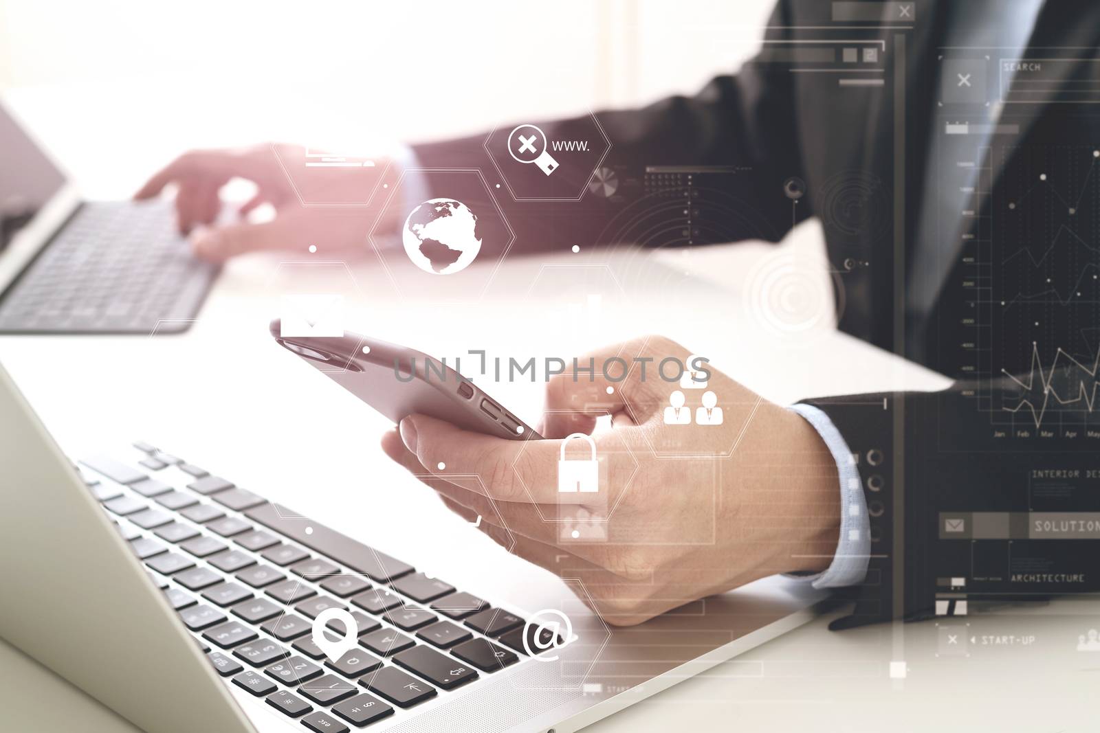 Hands of businessman using mobile phone in modern office with laptop and digital tablet computer with VR icon diagram