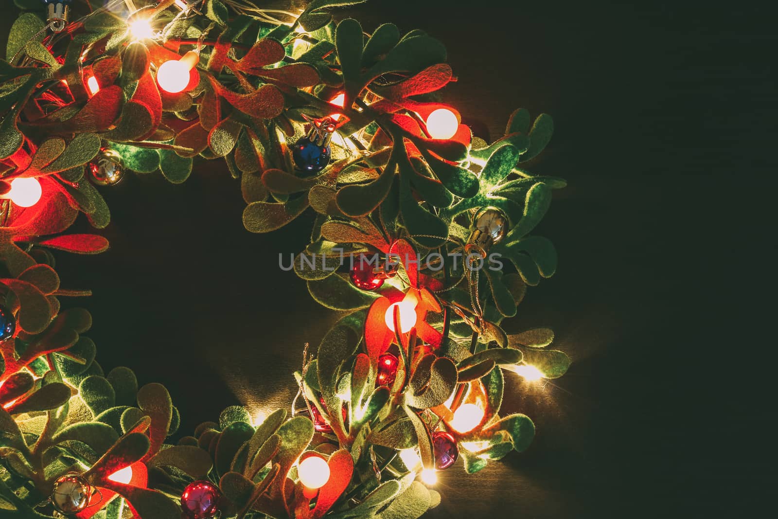 Greeting Season concept.Christmas wreath with decorative light on dark wood background