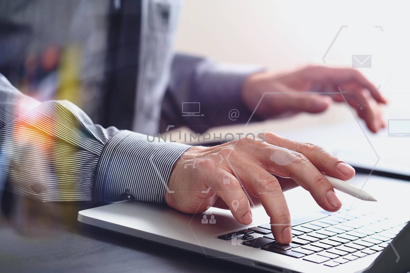 close up of businessman working with mobile phone and stylus pen and laptop computer  on wooden desk in modern office with virtual icon diagram