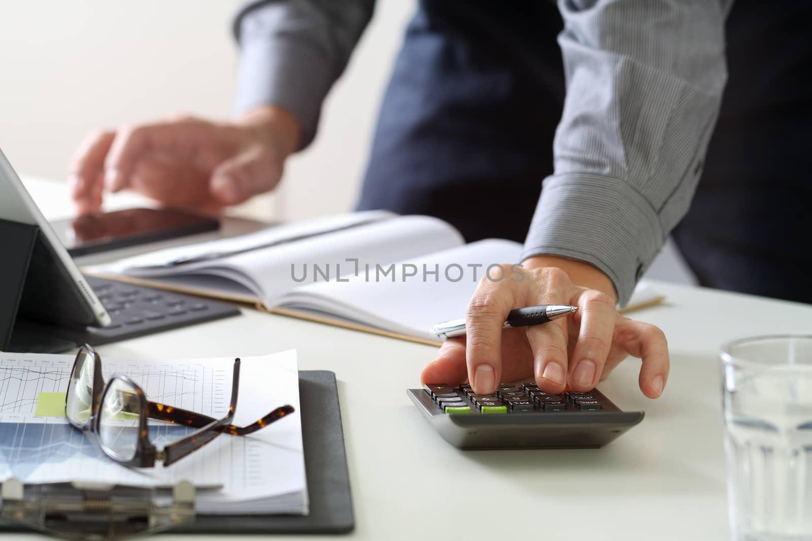 businessman hand working with finances about cost and calculator and latop with mobile phone on withe desk in modern office 