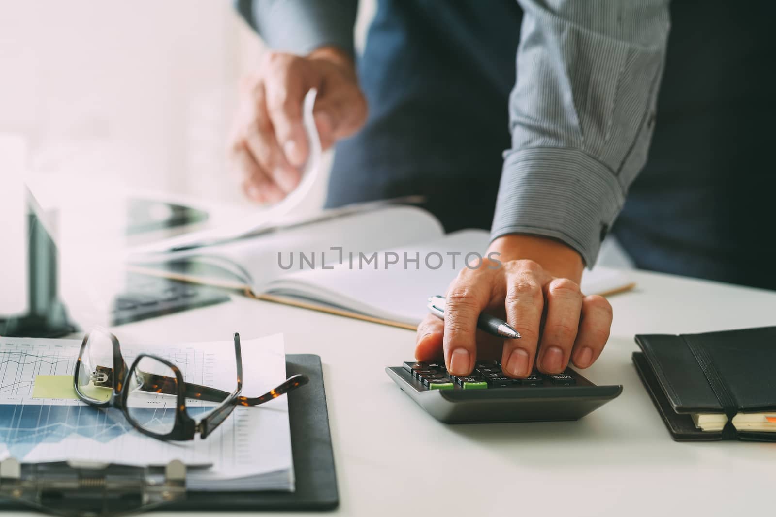 businessman hand working with finances about cost and calculator and latop with mobile phone on withe desk in modern office 