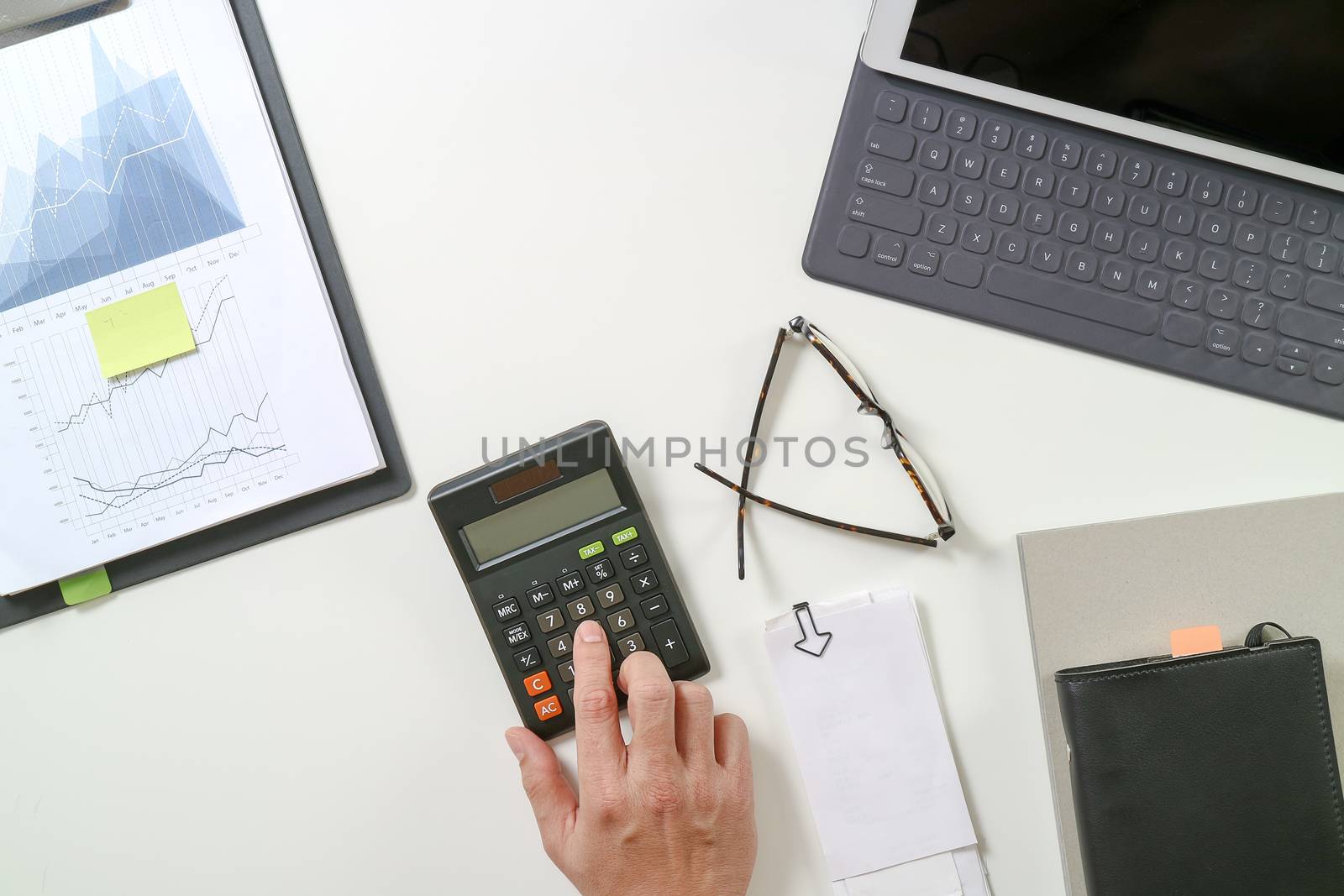 top view of businessman hand working with finances about cost and calculator and latop with mobile phone on withe desk in modern office 