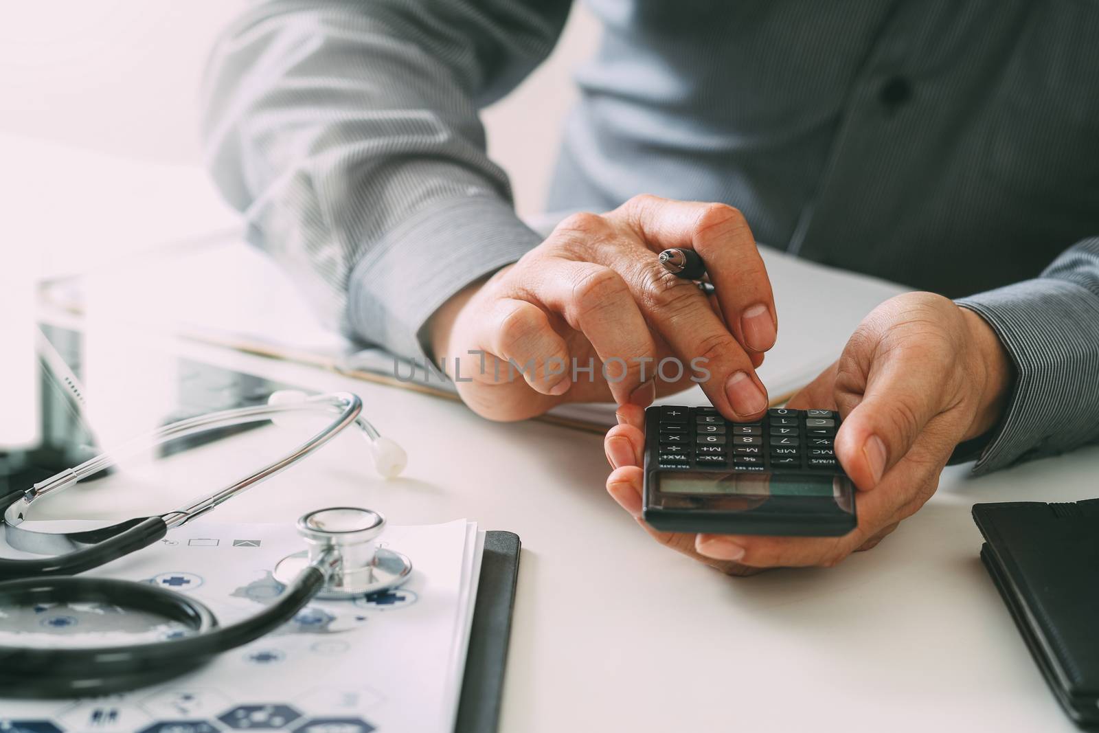 Healthcare costs and fees concept.Hand of smart doctor used a calculator for medical costs in modern hospital 