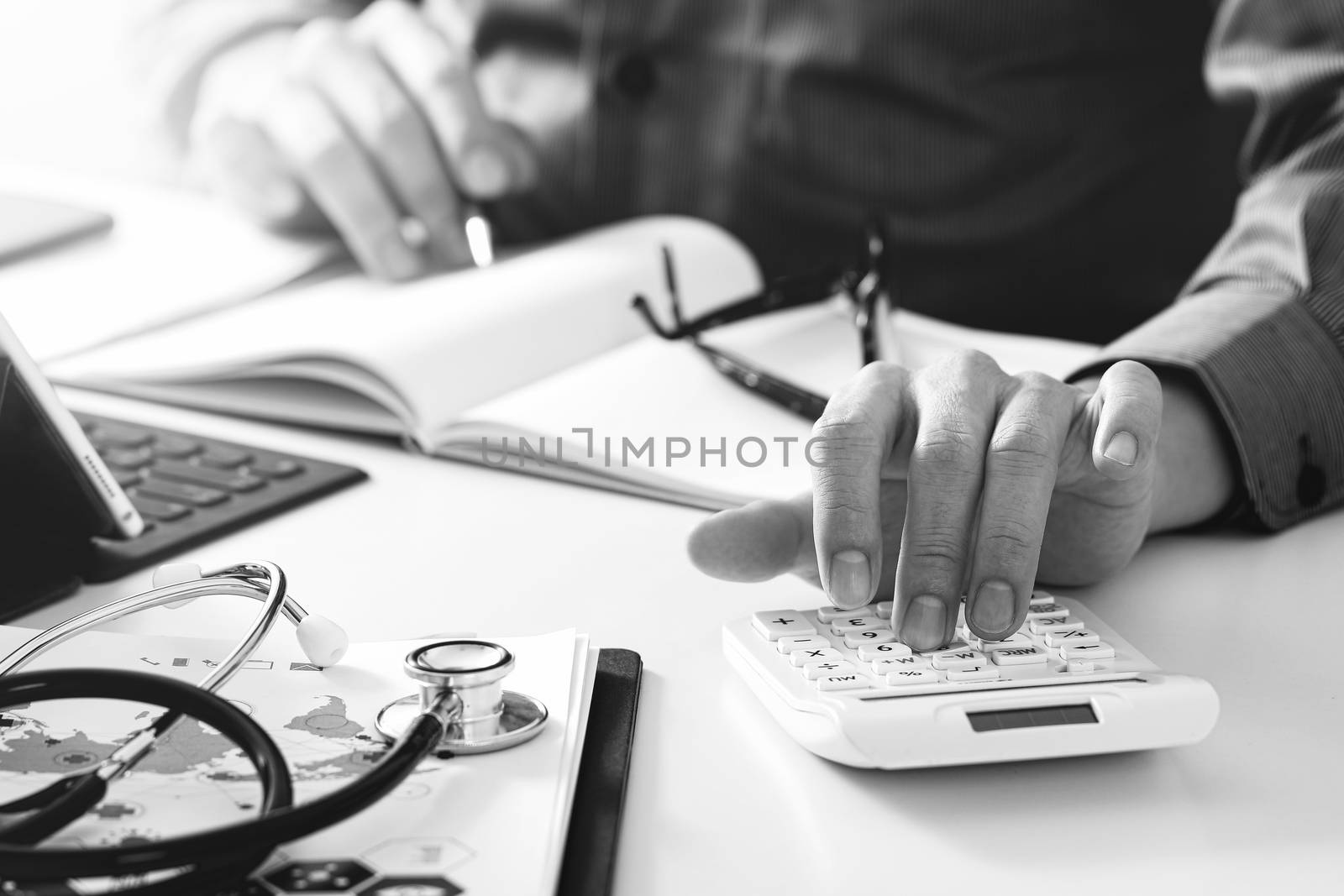 Healthcare costs and fees concept.Hand of smart doctor used a calculator for medical costs in modern hospital,black and white