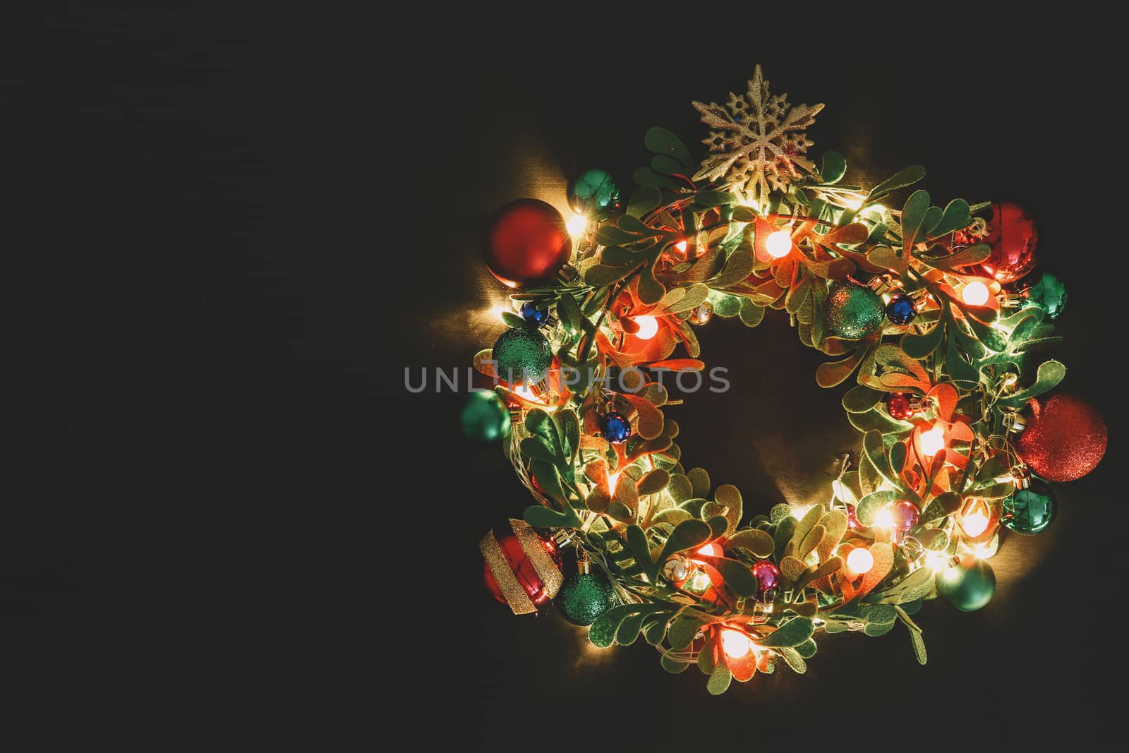 Greeting Season concept.Christmas wreath with decorative light on dark wood background