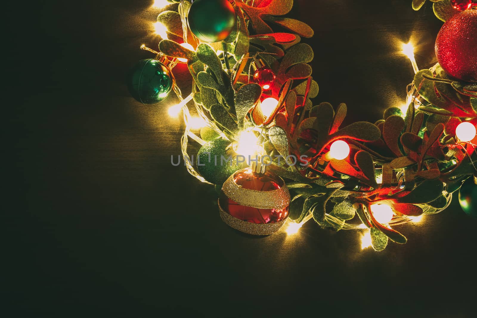 Greeting Season concept.Christmas wreath with decorative light on dark wood background