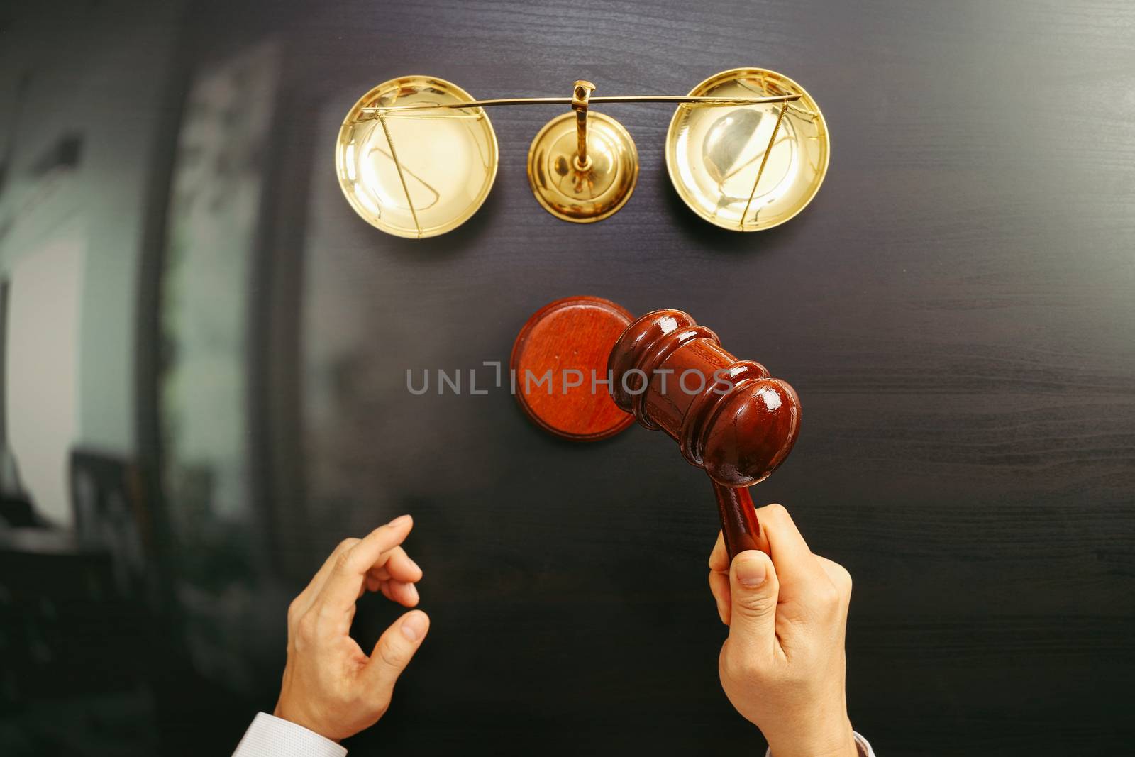 justice and law concept.Top view of Male judge hand in a courtroom with the gavel and brass scale on dark wood table