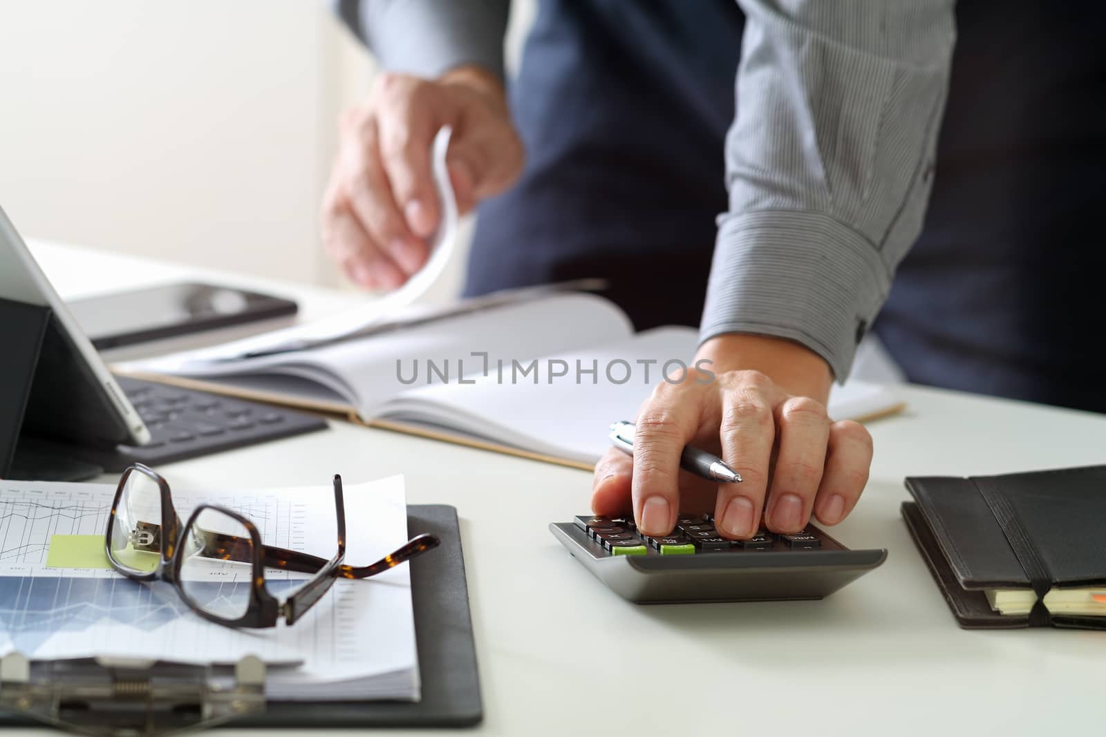 businessman hand working with finances about cost and calculator and latop with mobile phone on withe desk in modern office 