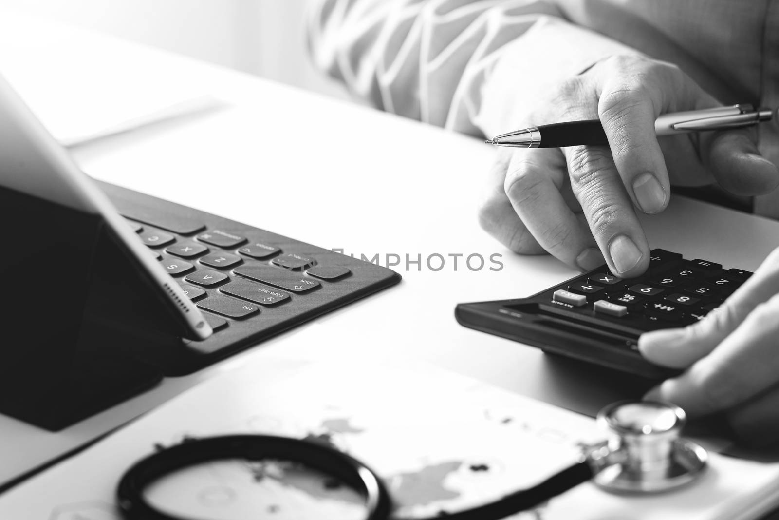 Healthcare costs and fees concept.Hand of smart doctor used a calculator for medical costs in modern hospital,black and white