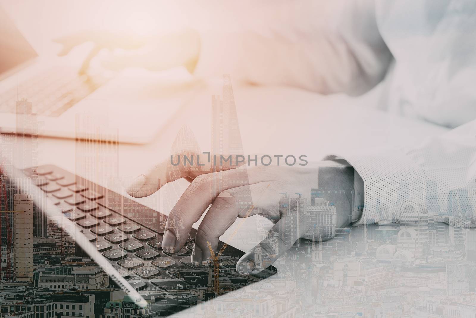 close up of businessman typing keyboard with laptop computer and digital tablet on white desk in modern office with city exposure