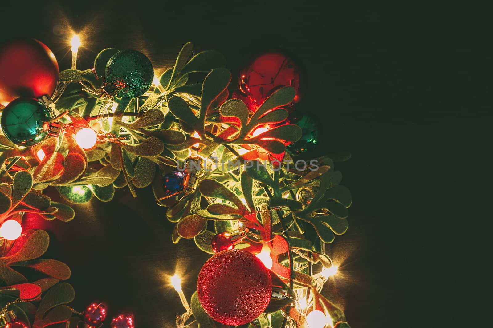 Greeting Season concept.Christmas wreath with decorative light on dark wood background